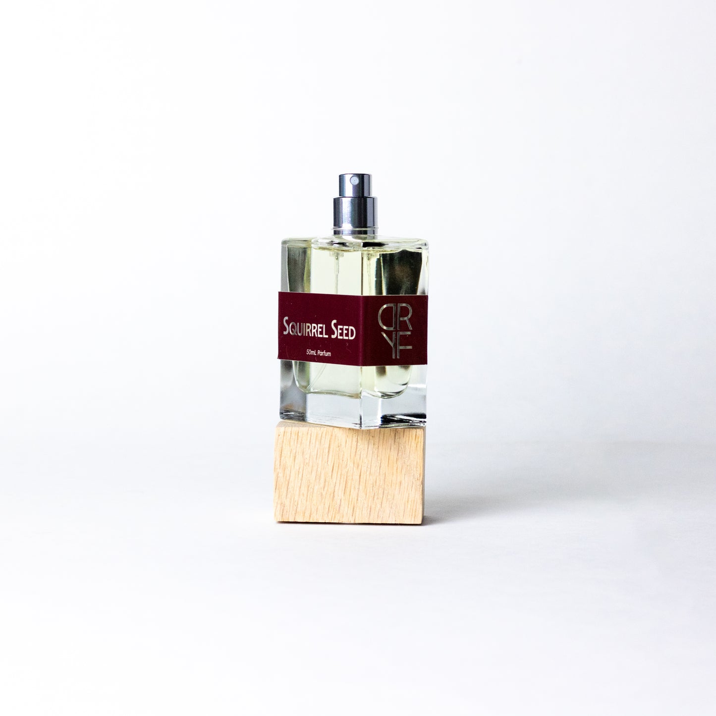Unisex fragrance Squirrel Seed by DRYF, blending bright ginger, lime, and pomegranate with earthy woods and musks for a nature-inspired scent.