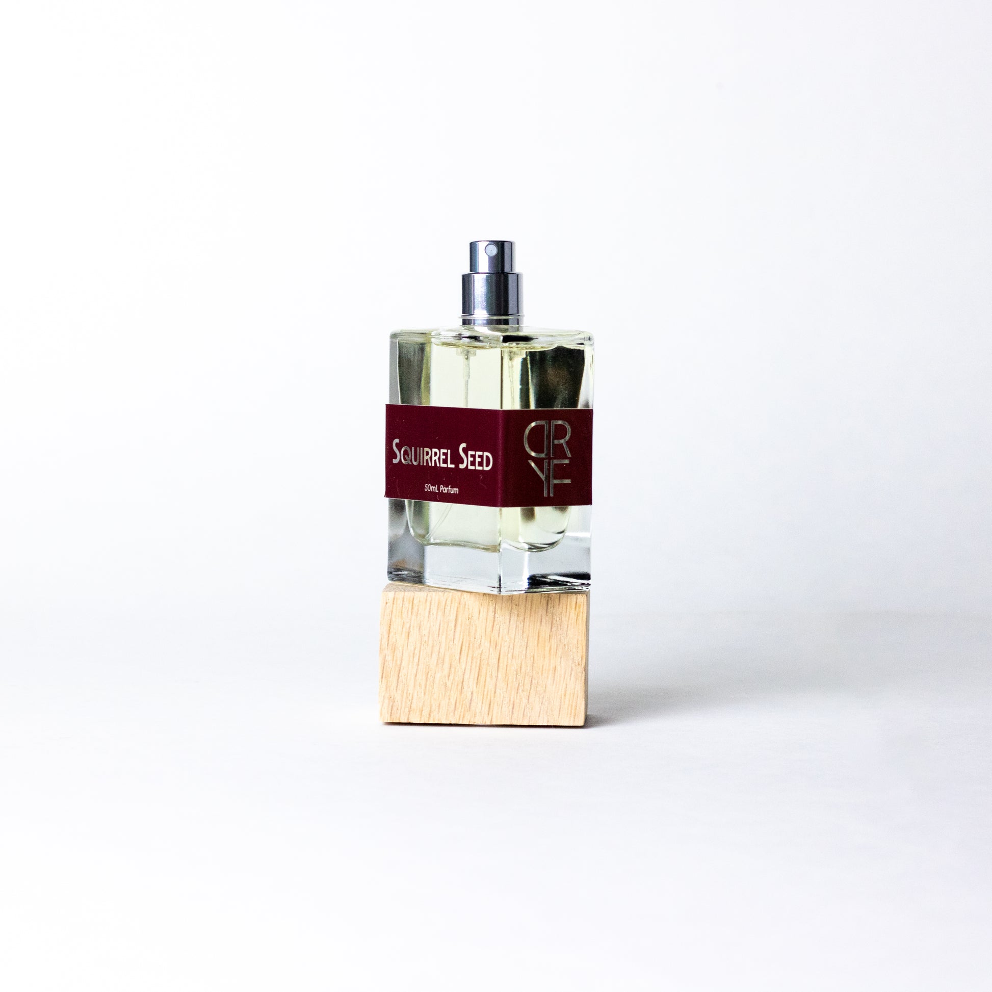 Unisex fragrance Squirrel Seed by DRYF, blending bright ginger, lime, and pomegranate with earthy woods and musks for a nature-inspired scent.