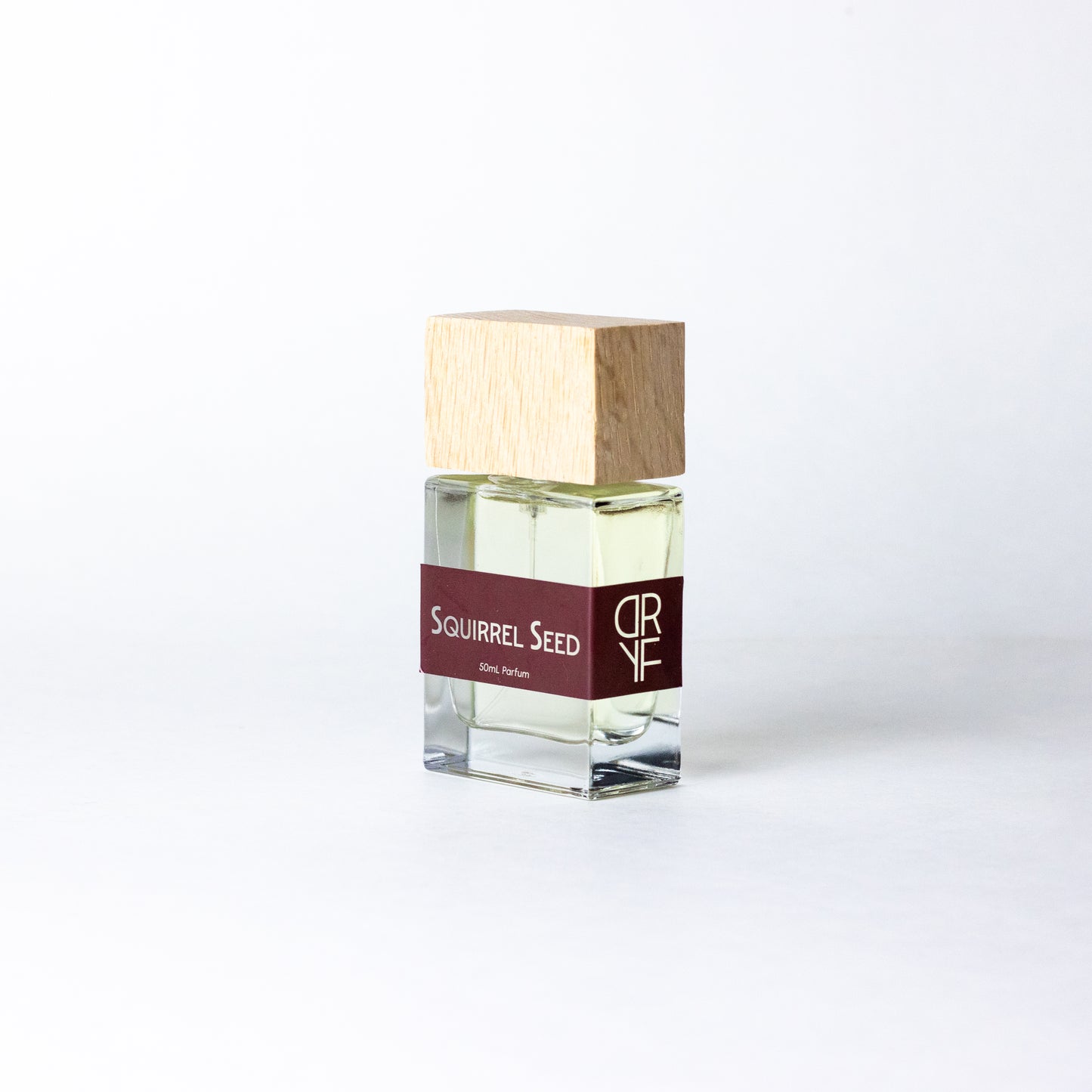 Handcrafted unisex fragrance Squirrel Seed by DRYF, featuring ginger, lime, and pomegranate balanced by earthy woods and deep musks.